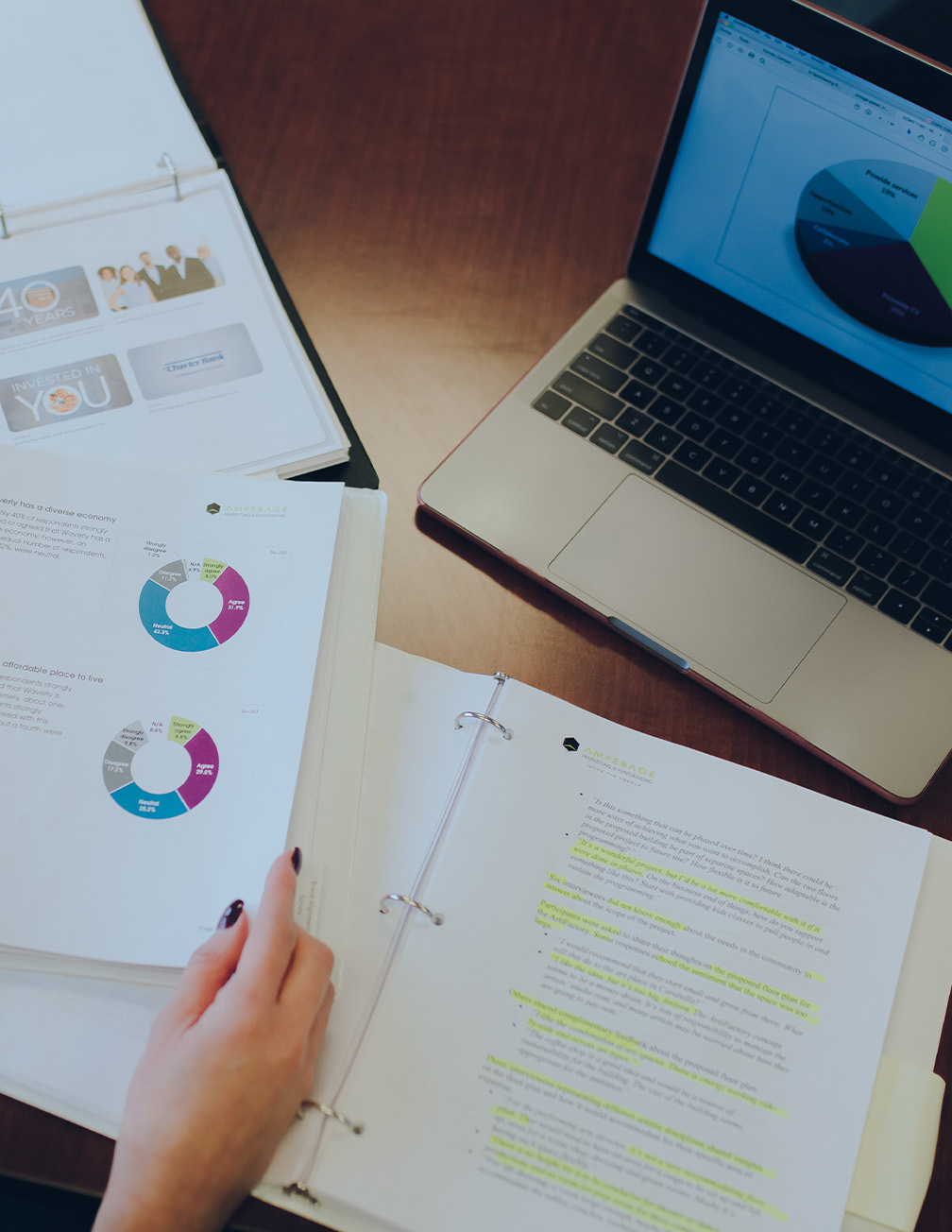 binder open on desk in front of computer showing graphs