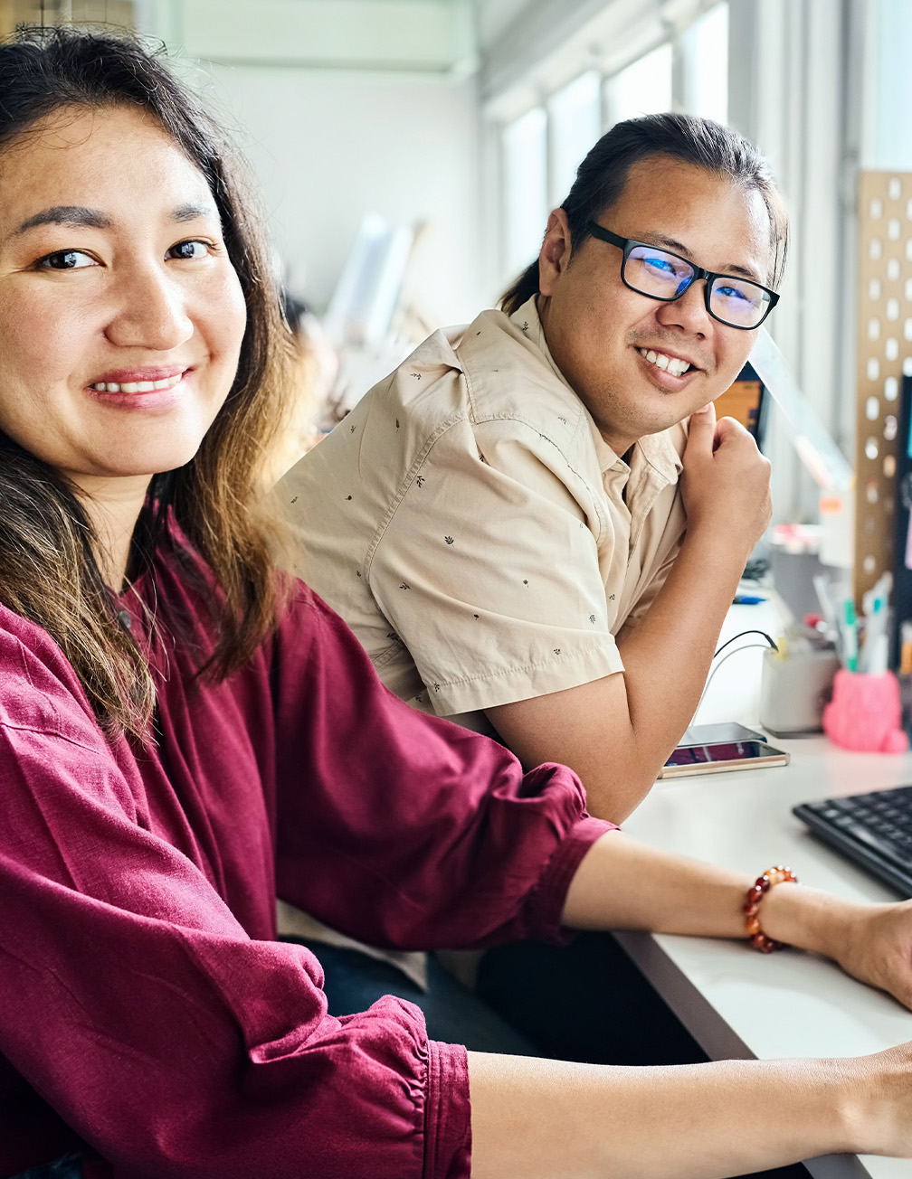 man and woman smiling at camera in front of computer